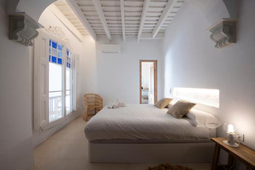 a white bedroom with a bed and a window at Casa Concha Apartamentos in Calella de Palafrugell