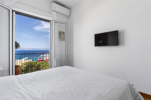 a white bedroom with a bed and a large window at On The Port in Rafina