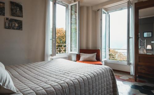 a bedroom with a bed and two large windows at B&B Villa le Ortensie in Faggeto Lario 