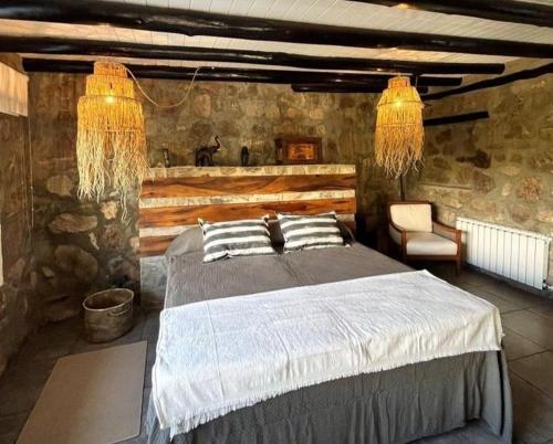 a bedroom with a large bed in a stone wall at Establecimiento La Soleada suites de campo in La Cumbre