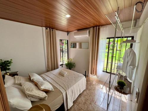 a bedroom with a bed in a room with windows at Casa Tropical Ceiba in Puerto Jiménez