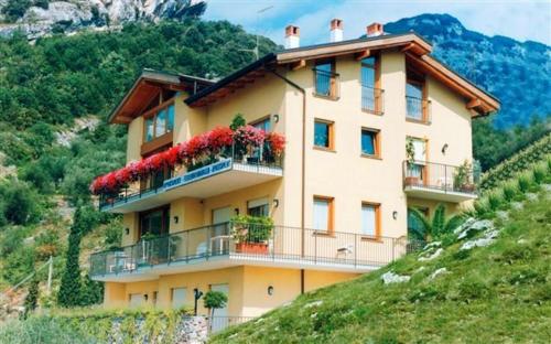 a building on a hill with flowers on it at Appartamenti Nido d'Aquila - Garda Lake View in Nago-Torbole
