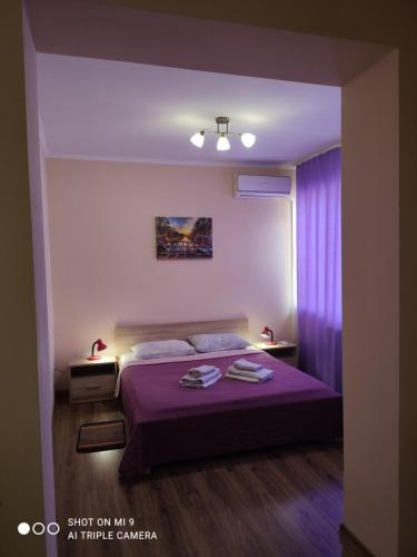 a bedroom with a purple bed with two towels on it at Apartments Domovik Parkaniya, 2A in Mukacheve