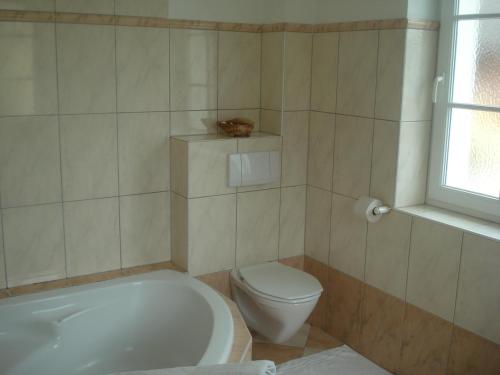 a bathroom with a tub and a toilet and a window at Landhaus Ferk in Unterburg am Klopeiner See