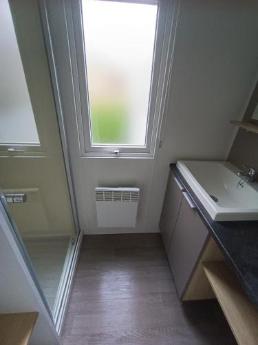 une petite salle de bain avec un lavabo et une fenêtre dans l'établissement mobil home 3 chambres 152, à Pont-Aven
