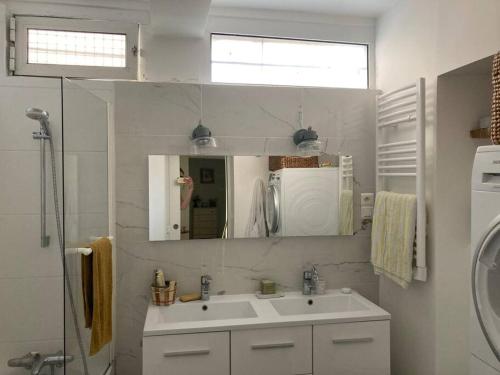 ein weißes Badezimmer mit einem Waschbecken und einem Spiegel in der Unterkunft Apartment in a charming house in Asnières-sur-Seine