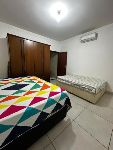 um quarto com uma cama com um edredão colorido em Casa de Campo Chácara Divisa Rio Preto e Guapiaçu em Sao Jose do Rio Preto