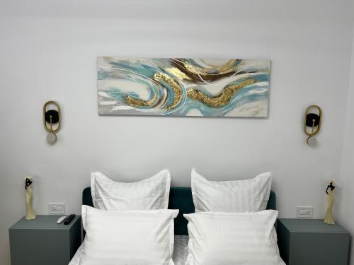 um quarto com almofadas brancas e uma pintura na parede em Style Central em Bucareste