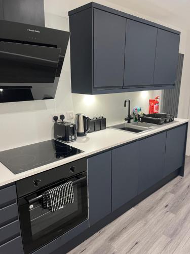 a kitchen with black cabinets and a stove top oven at The Boyd - Coorie Doon in Prestwick