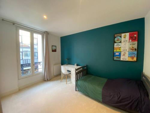 a bedroom with a blue wall with a bed and a desk at Dupleix Boulogne plein centre in Boulogne-Billancourt