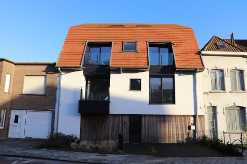 a white house with an orange roof at Prachtig duplex appartement met balkon te Wenduine in De Haan