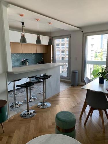 une cuisine avec un comptoir et des tabourets dans une pièce dans l'établissement *Cosy and sweet Apartment* Paris Défense* Porte maillot, à Puteaux