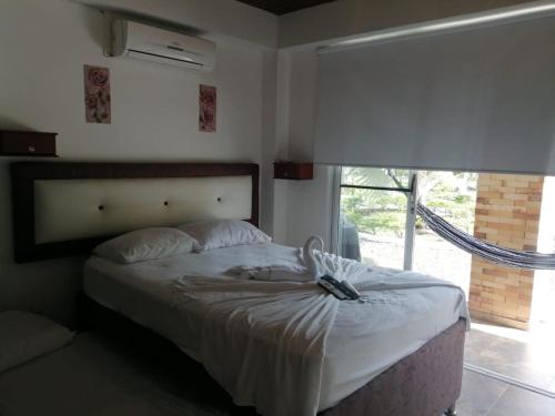 Una cama en un dormitorio con una ventana grande. en Finca Hotel Mesopotamia, en Restrepo