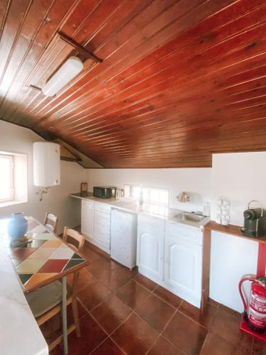een keuken met witte kasten en een houten plafond bij Casa Wanderlust in Sintra