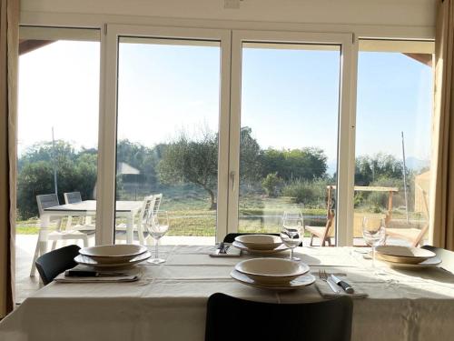 une table à manger avec une nappe et des chaises blanches ainsi que des fenêtres dans l'établissement Orto della Lepre, à Montemaggiore al Metauro
