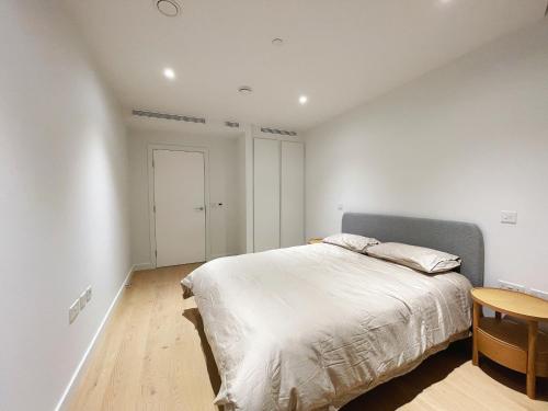 a white bedroom with a bed and a wooden table at Modern apartment in heart area in London