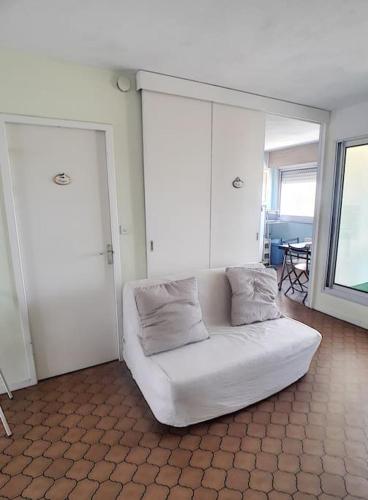 - un canapé blanc avec deux oreillers dans l'établissement Appartement belle vue sur mer - 4425, à Soulac-sur-Mer