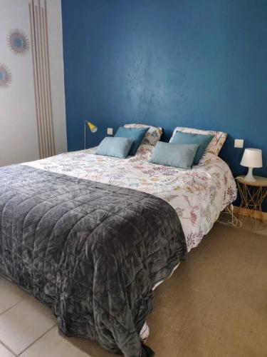 une chambre avec un grand lit avec un mur bleu dans l'établissement Maison 3 étoiles avec piscine et jacuzzi extérieur près de Sarlat, à Saint-Vincent-le-Paluel