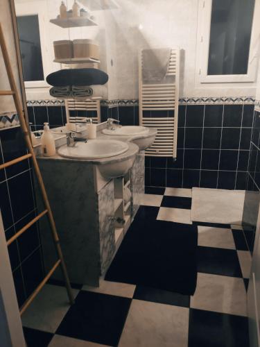 La salle de bains est pourvue de deux lavabos et de carrelage noir et blanc. dans l'établissement Maison 3 étoiles avec piscine et jacuzzi extérieur près de Sarlat, à Saint-Vincent-le-Paluel