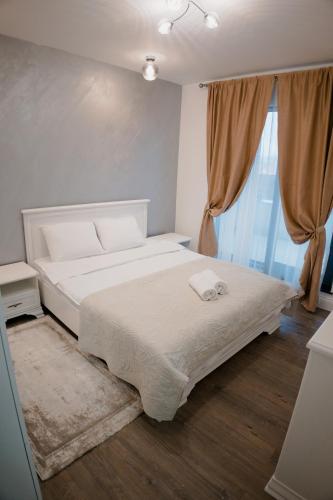 a bedroom with a large white bed and a window at Oasului Residence in Cluj-Napoca