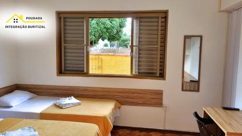 a room with two beds and a window at Pousada Integração Buritizal in Buritizal