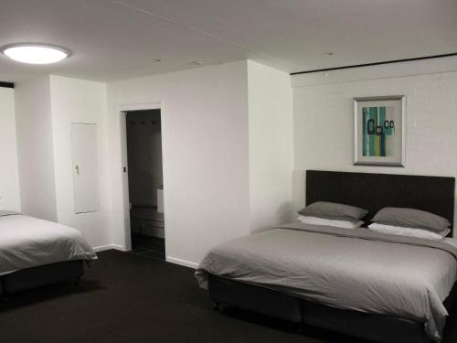 a bedroom with two beds in a room with white walls at Large Bright Modern Loft Apt - Central Location - Suitable for Families and Groups in Narrabundah