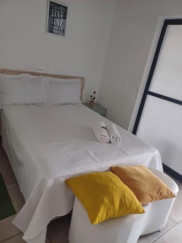 a white bed with two yellow pillows on it at Lindo Studio no bom Retiro prox ao anhembi Sambodromo com wifi in São Paulo