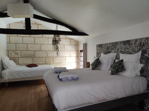une chambre avec un grand lit avec des draps blancs dans l'établissement Ancien moulin rénové proche de Bordeaux, à Carignan