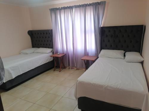una camera d'albergo con due letti e una finestra di JJP SELF CATERING - Three bedroom house a Lüderitz