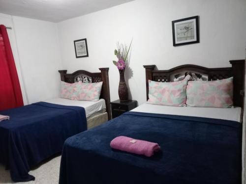 1 dormitorio con 2 camas con sábanas azules y toalla morada en Historico maya, en Guatemala