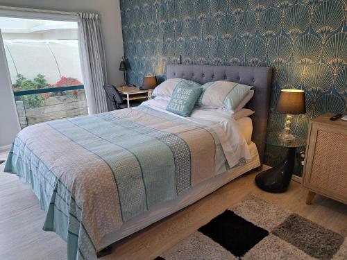 a bedroom with a bed with a blue patterned wall at Sunbrae Beach Sanctuary free high Fibre wifi in Mount Maunganui