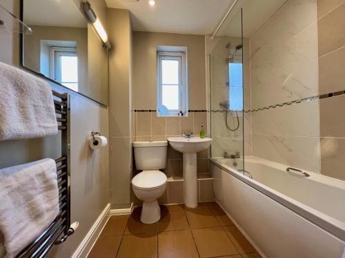 a bathroom with a toilet and a tub and a sink at The Orchid-Central Beeston-Private Apartment-SmartTV-Free Wi-Fi-Tram-Parking in Nottingham