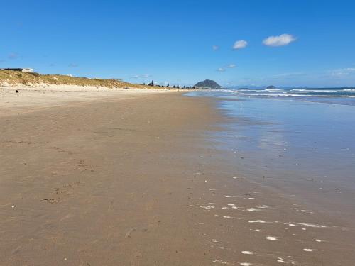 a beach with footprints in the sand and the ocean at Sunbrae Beach Sands Y in Mount Maunganui