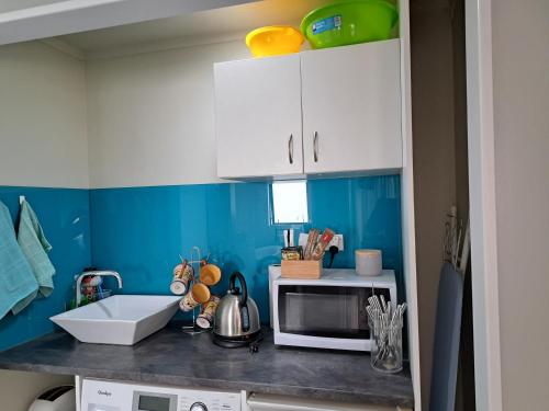 a kitchen with blue walls and white cabinets at Sunbrae Beach in Mount Maunganui