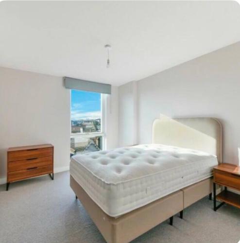 a bedroom with a bed and a dresser and a window at VG Apartments 2 Bedroom LDN in London