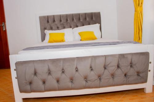 a bed with a gray and white bed frame and yellow pillows at Deci Homes in Ruaka