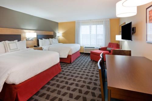 a hotel room with two beds and a desk at TownePlace Suites by Marriott Sioux Falls South in Sioux Falls