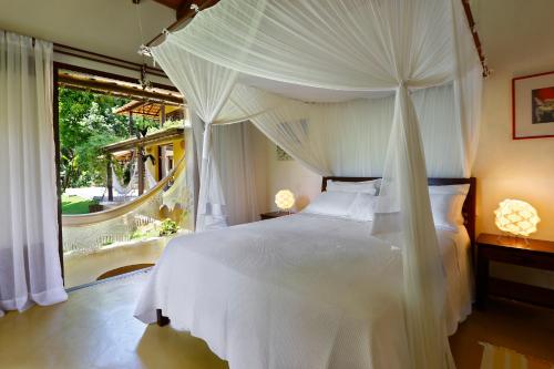 a bedroom with a white bed and a large window at Casa Baiana Pousada & Aconchego in Trancoso
