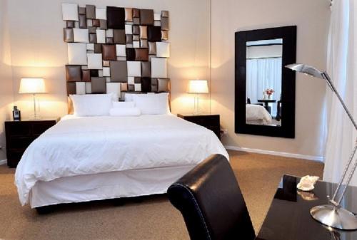 a bedroom with a large white bed and a mirror at A Villa de Mer Guesthouse in Port Alfred