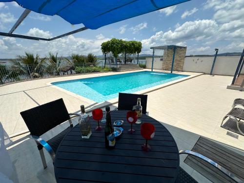 una mesa con copas de vino junto a una piscina en Casa Florida do Lago en Guapé