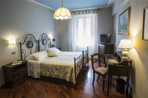 Schlafzimmer mit einem Bett, einem Schreibtisch und einem TV in der Unterkunft La Locanda Del Capitano in Montone