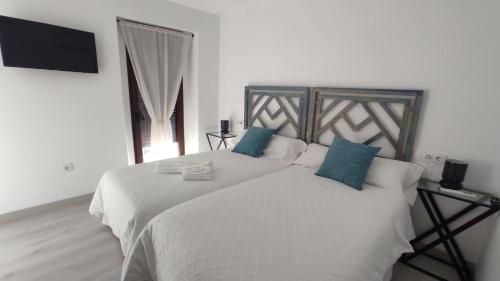 um quarto com uma grande cama branca com almofadas azuis em CASA RURAL ELENYR em Calera de León