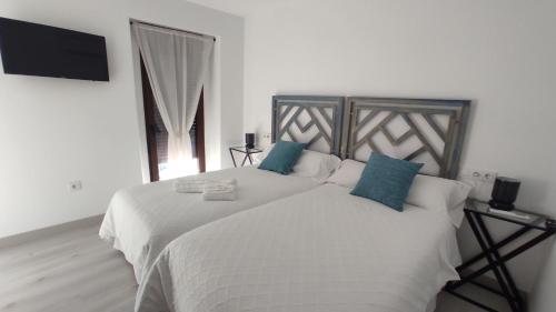 a bedroom with a large white bed with blue pillows at CASA RURAL ELENYR in Calera de León