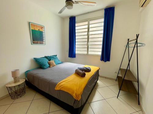 1 dormitorio con 1 cama con manta amarilla y ventana en L'échappée bleue, en Faaa