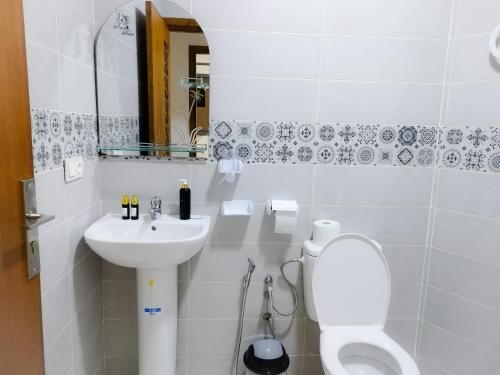 La salle de bains blanche est pourvue de toilettes et d'un lavabo. dans l'établissement les Belles Résidences de Safir, à Tanger