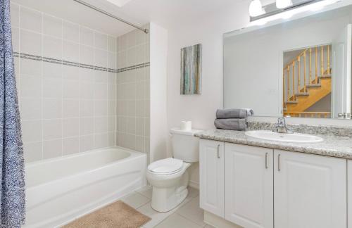a white bathroom with a tub and a toilet and a sink at 4 Bedroom Oshawa house in Oshawa