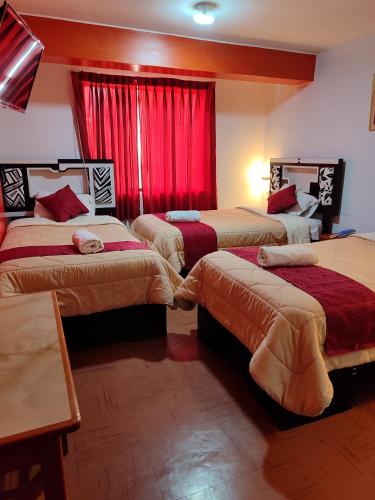 a hotel room with three beds with red curtains at Krusty Hostel B&B in Huaraz