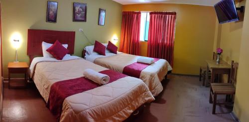 a hotel room with two beds with red curtains at Krusty Hostel B&B in Huaraz