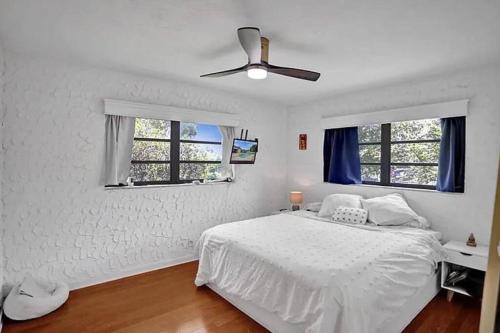 a white bedroom with a bed and a ceiling fan at Stylish palm beach home with pool and office in Palm Beach Gardens