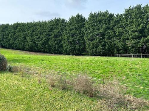 a fence in a field with trees in the background at La Maison Verte in Clécy
